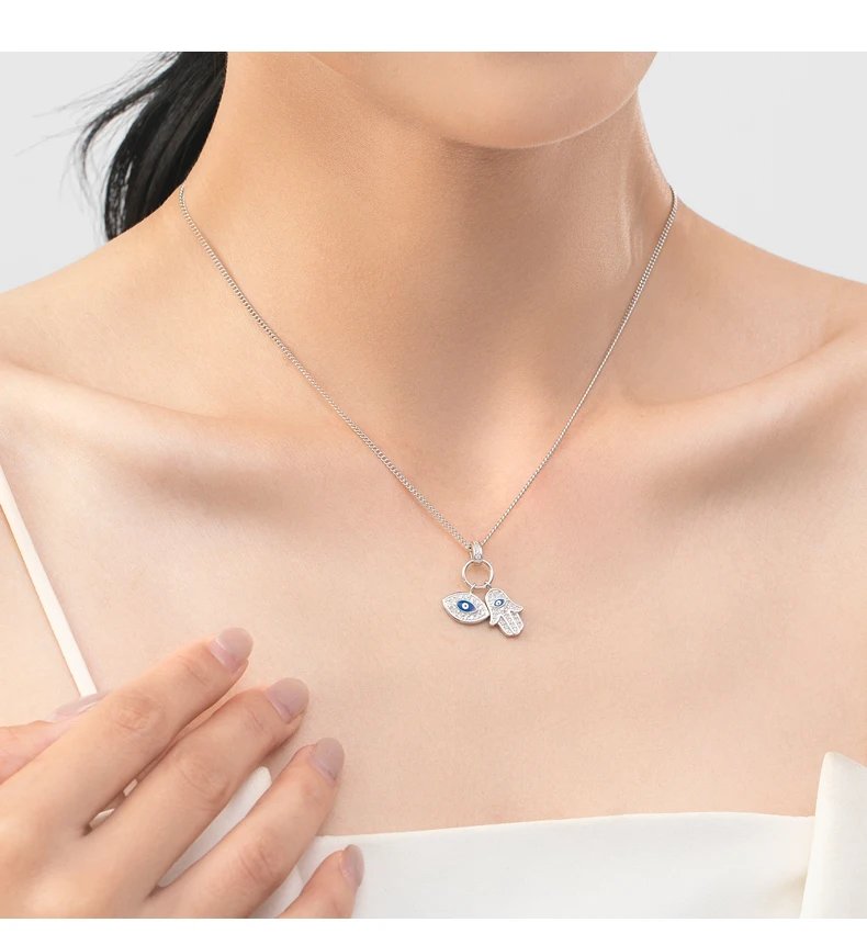 Aziza Hamsa and evil eye CZ necklace worn by a woman with silver chain and sparkling blue eye charms